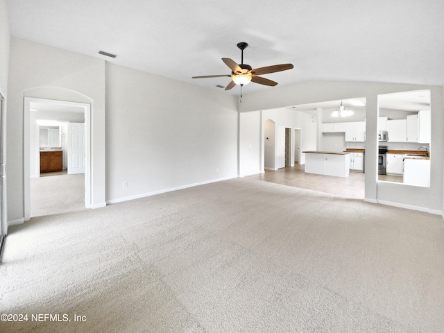 unfurnished living room with light carpet, sink, ceiling fan, and vaulted ceiling