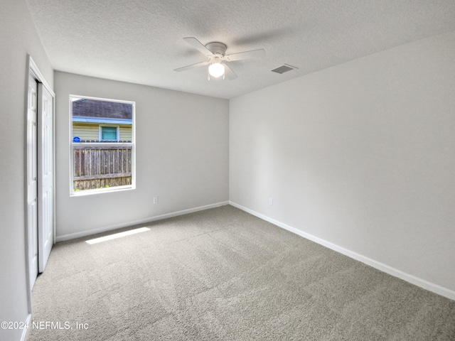 carpeted empty room featuring ceiling fan and a textured ceiling