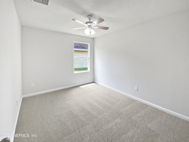 empty room with carpet flooring, ceiling fan, and a textured ceiling