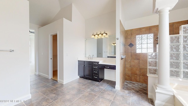 bathroom featuring vanity, lofted ceiling, tiled shower, and decorative columns