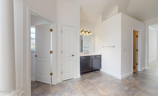 bathroom with tile patterned flooring, vanity, and vaulted ceiling