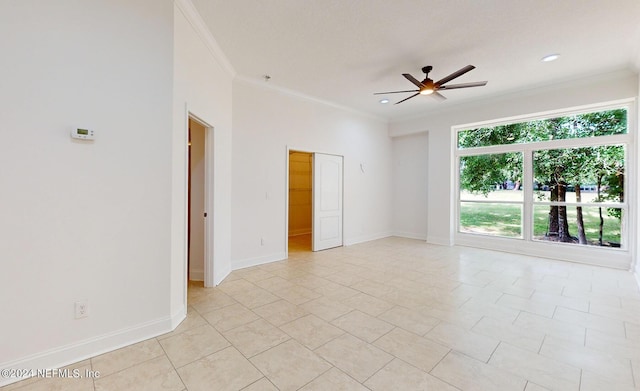 empty room with ceiling fan, ornamental molding, and light tile patterned floors