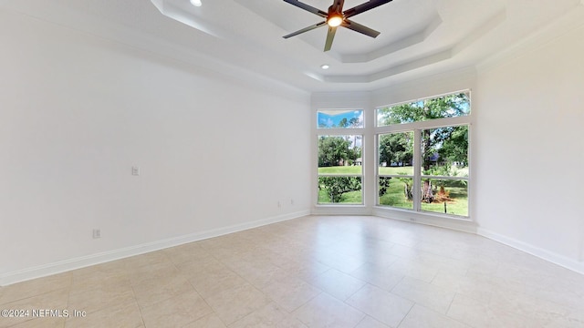 unfurnished room with a tray ceiling, ceiling fan, a towering ceiling, and light tile patterned floors