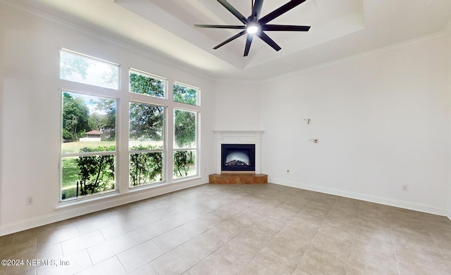 unfurnished living room with a tray ceiling, ceiling fan, a healthy amount of sunlight, and ornamental molding