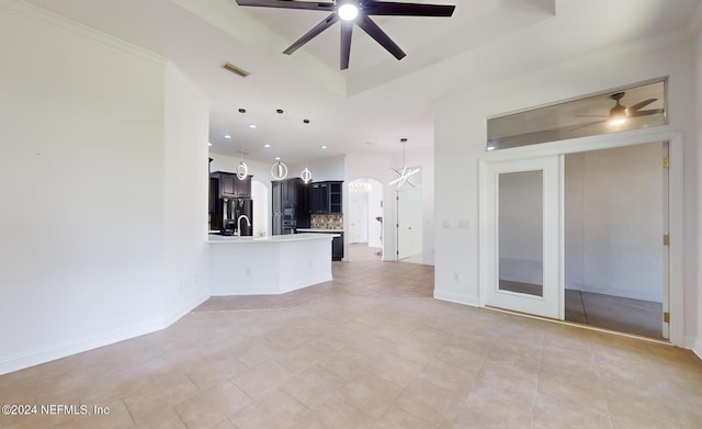 unfurnished living room with a tray ceiling, ceiling fan, crown molding, and light tile patterned flooring