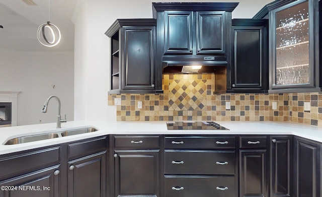 kitchen featuring tasteful backsplash, black cooktop, sink, and hanging light fixtures