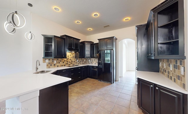 kitchen with backsplash, black appliances, sink, decorative light fixtures, and kitchen peninsula