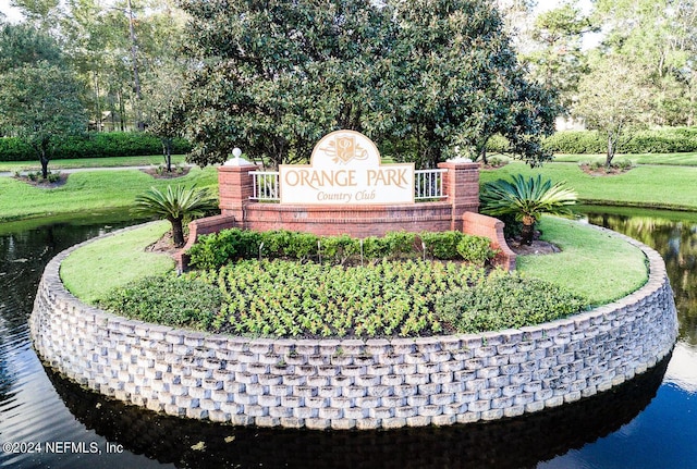 community / neighborhood sign with a yard and a water view