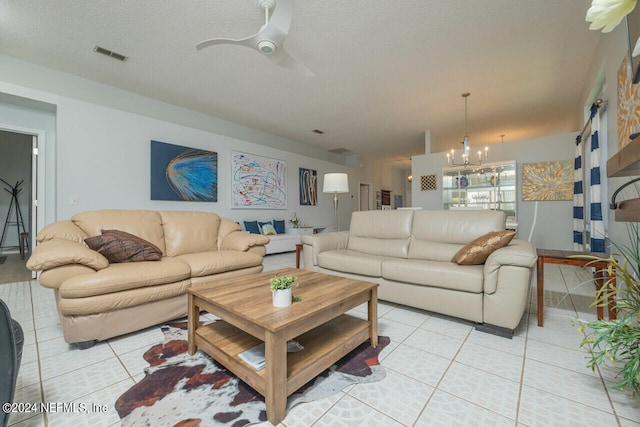 living room with a textured ceiling, light tile patterned floors, and ceiling fan with notable chandelier