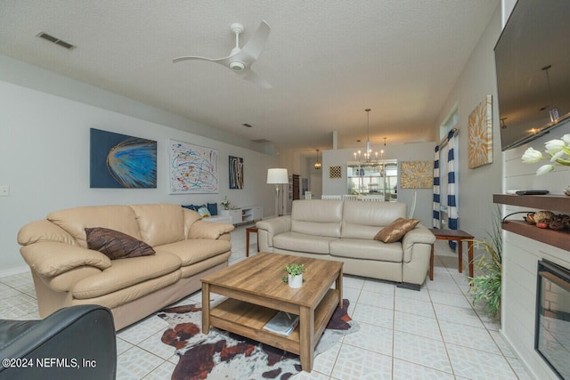 tiled living room featuring ceiling fan with notable chandelier and a textured ceiling