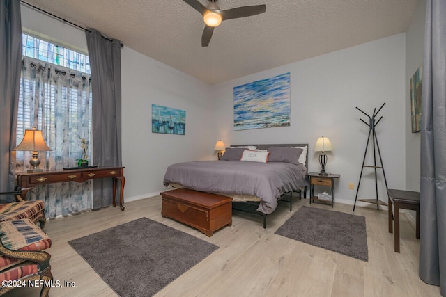 bedroom with a textured ceiling, light hardwood / wood-style floors, and ceiling fan