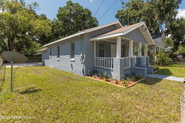 view of home's exterior with covered porch, a lawn, and fence