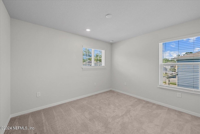 spare room with a textured ceiling and carpet flooring