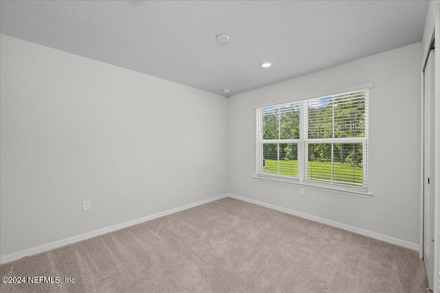 carpeted empty room featuring a textured ceiling