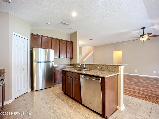 kitchen featuring lofted ceiling, a kitchen island with sink, sink, light hardwood / wood-style flooring, and appliances with stainless steel finishes