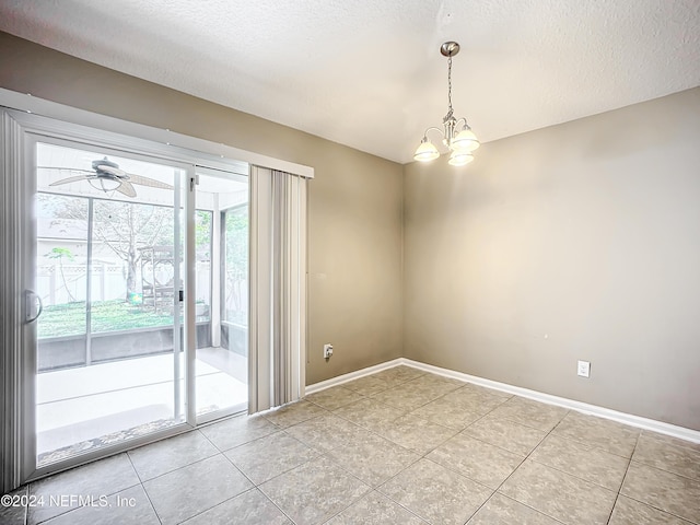 tiled spare room with ceiling fan with notable chandelier and a textured ceiling