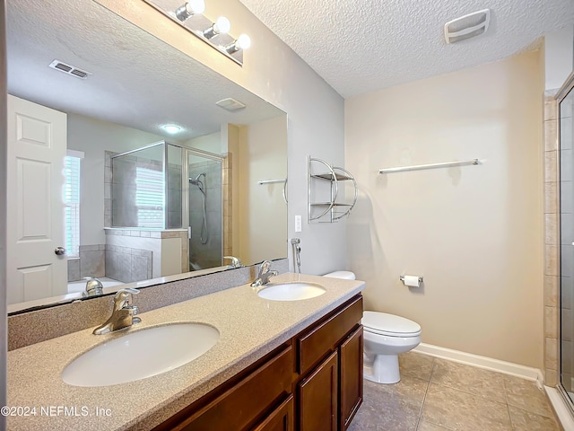 bathroom with vanity, a shower with door, tile patterned flooring, toilet, and a textured ceiling