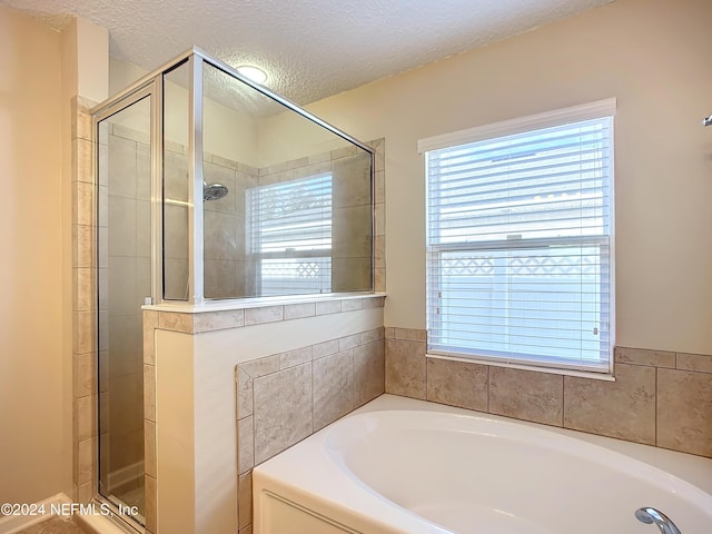 bathroom featuring separate shower and tub and a textured ceiling