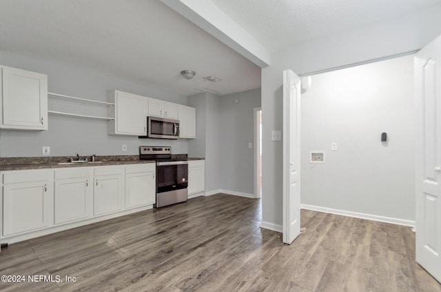 kitchen featuring dark countertops, appliances with stainless steel finishes, open shelves, and white cabinets