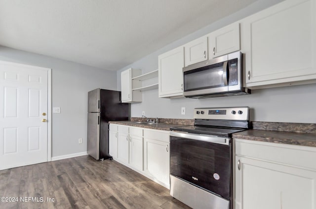 kitchen with stainless steel appliances, dark countertops, and white cabinets