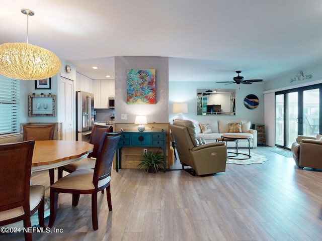 dining area with ceiling fan with notable chandelier and light hardwood / wood-style floors