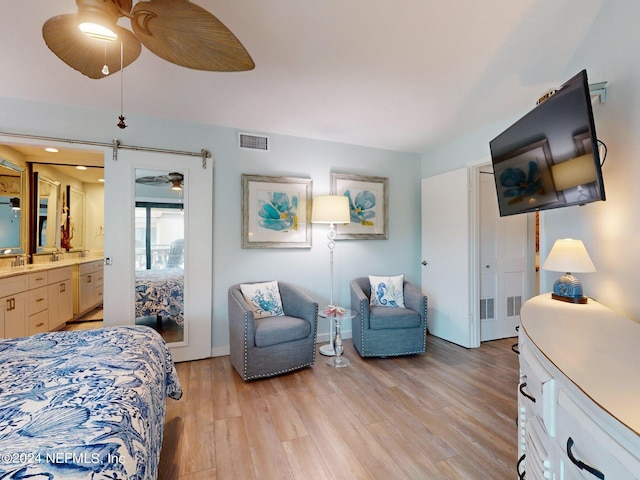 bedroom featuring light hardwood / wood-style floors, ceiling fan, and ensuite bath