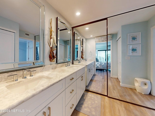 bathroom featuring backsplash, wood-type flooring, vanity with extensive cabinet space, and dual sinks