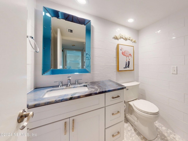 bathroom featuring tile flooring, tile walls, toilet, and large vanity