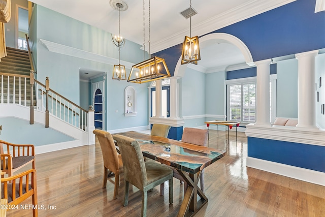 dining area featuring crown molding, an inviting chandelier, ornate columns, and hardwood / wood-style floors