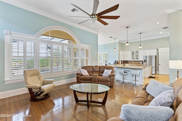 living room featuring ceiling fan, light hardwood / wood-style flooring, and crown molding