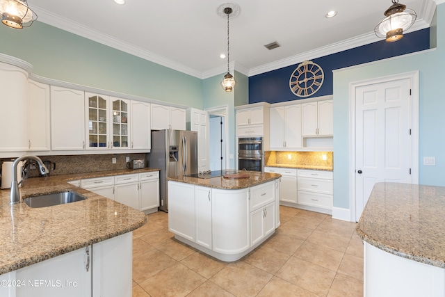 kitchen featuring tasteful backsplash, stainless steel appliances, pendant lighting, a center island, and sink