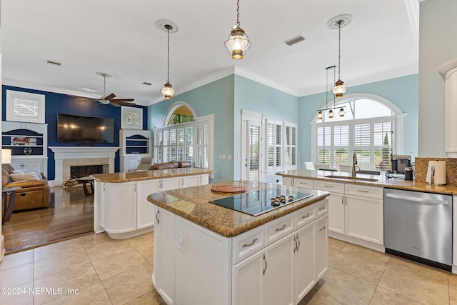 kitchen with a tiled fireplace, dishwasher, pendant lighting, a kitchen island, and white cabinetry