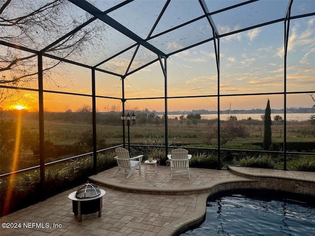 pool at dusk with a patio and a lanai