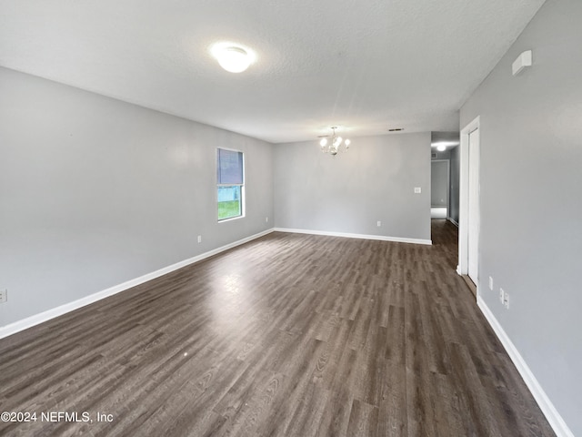 spare room with dark hardwood / wood-style floors and a chandelier