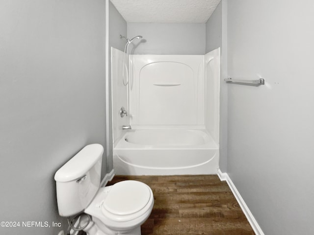 bathroom featuring wood-type flooring, a textured ceiling, toilet, and tub / shower combination