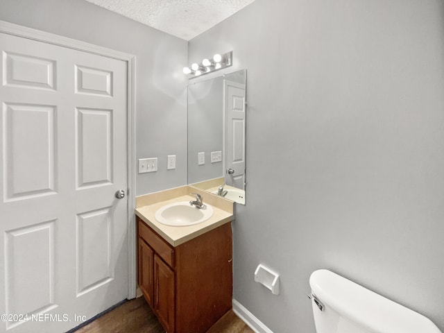 bathroom with a textured ceiling, oversized vanity, and toilet