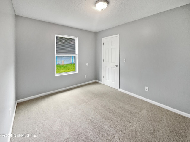 empty room with a textured ceiling and carpet flooring