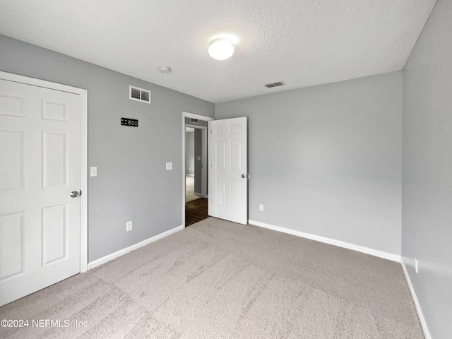 unfurnished bedroom featuring a textured ceiling and carpet