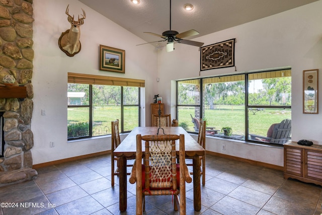 tiled dining space featuring a fireplace, a textured ceiling, high vaulted ceiling, and ceiling fan