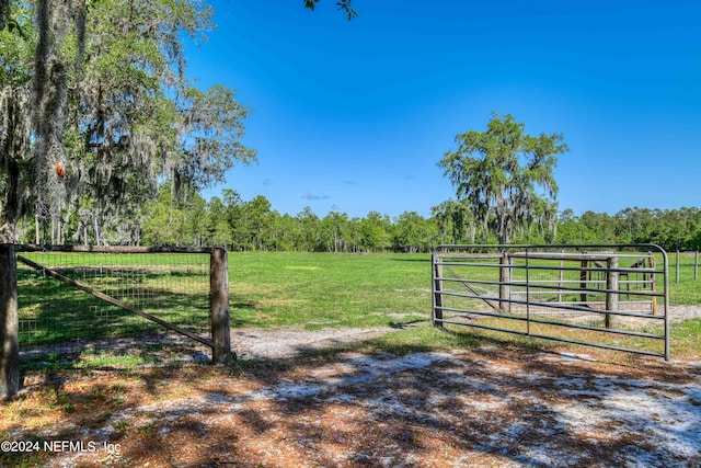 view of gate featuring a lawn and a rural view