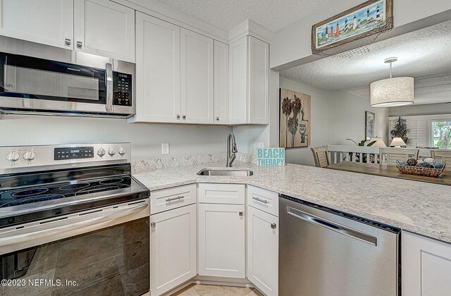 8550 A1A Unit 12122, Saint Augustine, FL 32080 - kitchen with white cabinetry, a textured ceiling, stainless steel appliances, pendant lighting, and sink