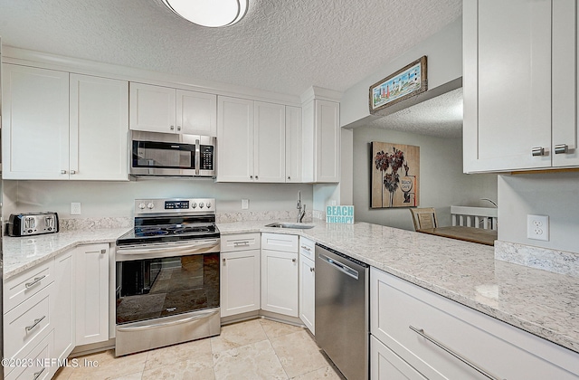 8550 A1A Unit 12122, Saint Augustine, FL 32080 - kitchen featuring a textured ceiling, stainless steel appliances, white cabinets, sink, and light tile floors