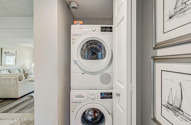 8550 A1A Unit 12122, Saint Augustine, FL 32080 - laundry area with a textured ceiling, hardwood / wood-style floors, and stacked washer and clothes dryer