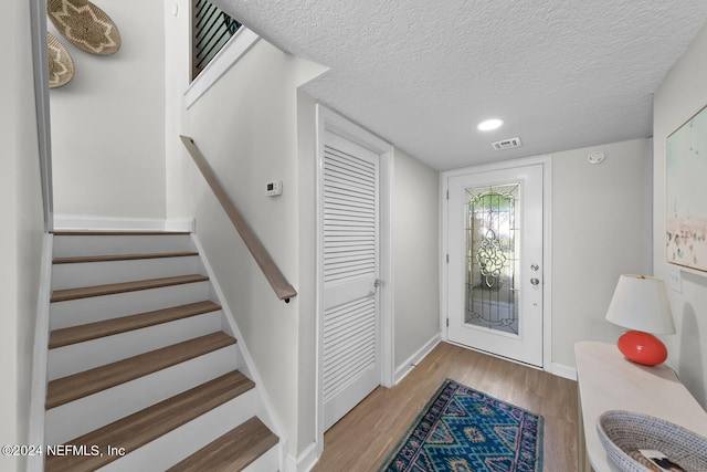 foyer entrance with wood-type flooring and a textured ceiling