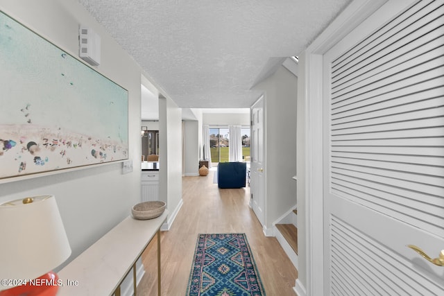 hall featuring a textured ceiling, light wood-type flooring, and french doors