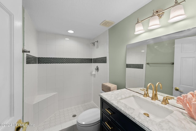 bathroom featuring toilet, vanity, and tiled shower