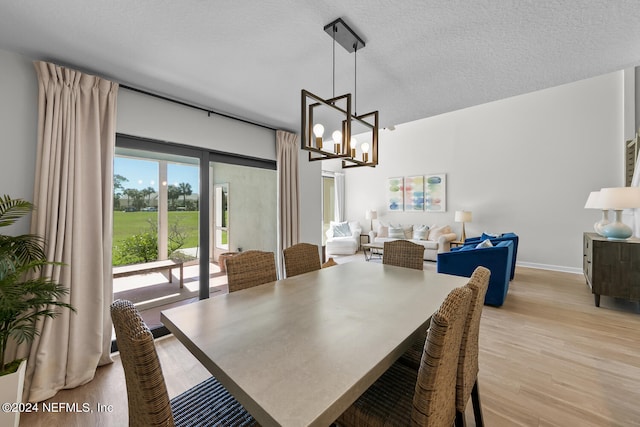 dining room with a textured ceiling, light hardwood / wood-style flooring, and a notable chandelier