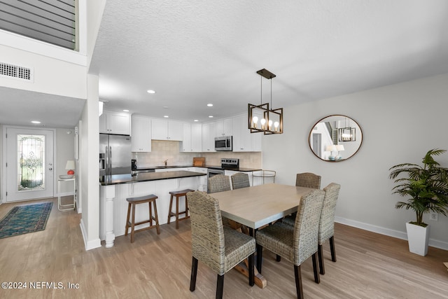 dining space with sink, a textured ceiling, and light hardwood / wood-style flooring