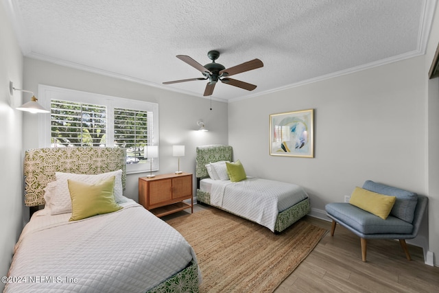 bedroom featuring ceiling fan, crown molding, a textured ceiling, and light wood-type flooring