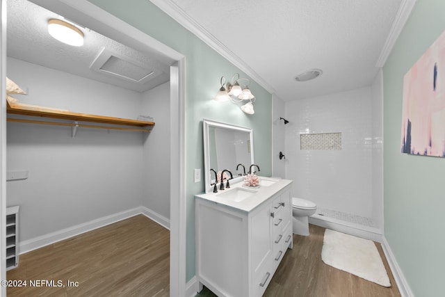 bathroom with vanity, hardwood / wood-style flooring, ornamental molding, tiled shower, and a textured ceiling